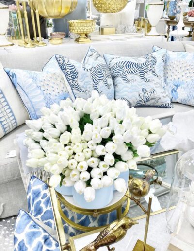 A couch with blue and white pillows and a gold vase.