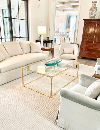 A living room with white furniture and a glass coffee table.