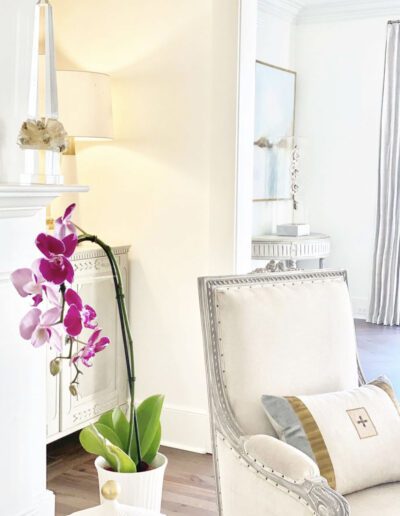 A white living room with a vase of orchids.