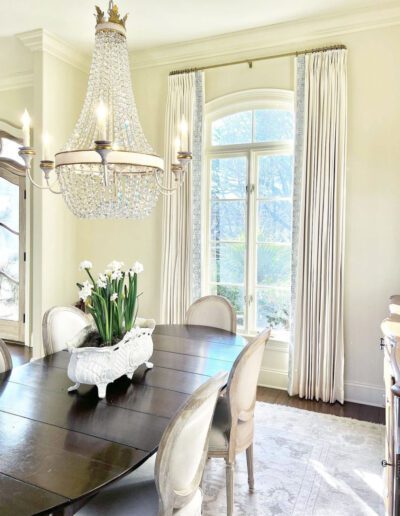 A dining room with a chandelier and chairs.